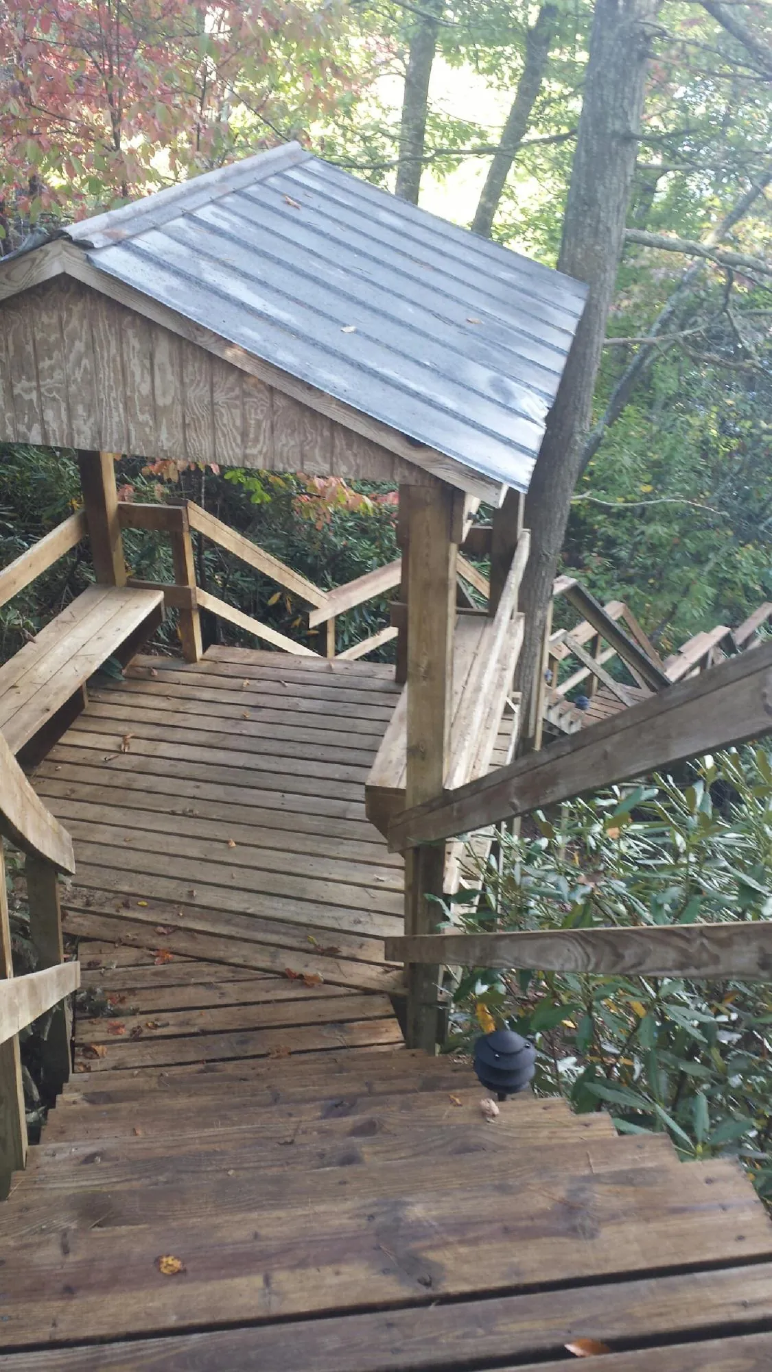 Metal roofed shelter over wooden steps on a wooded walkway — Skylight Repair & Installation work by our crew in Janesville